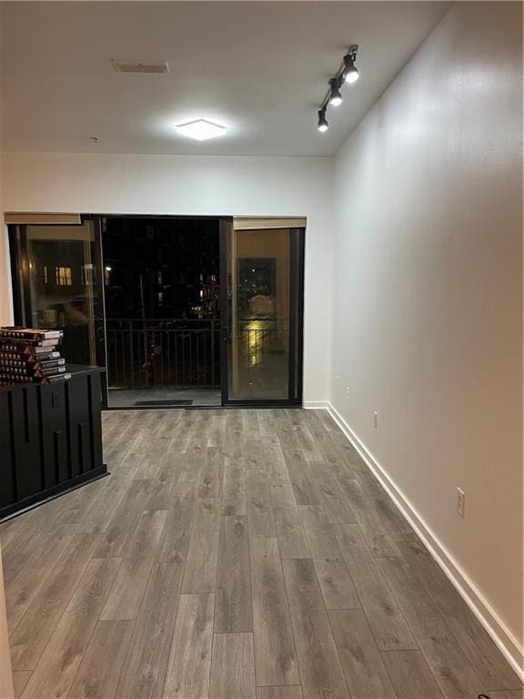 unfurnished room featuring wood finished floors, visible vents, and baseboards