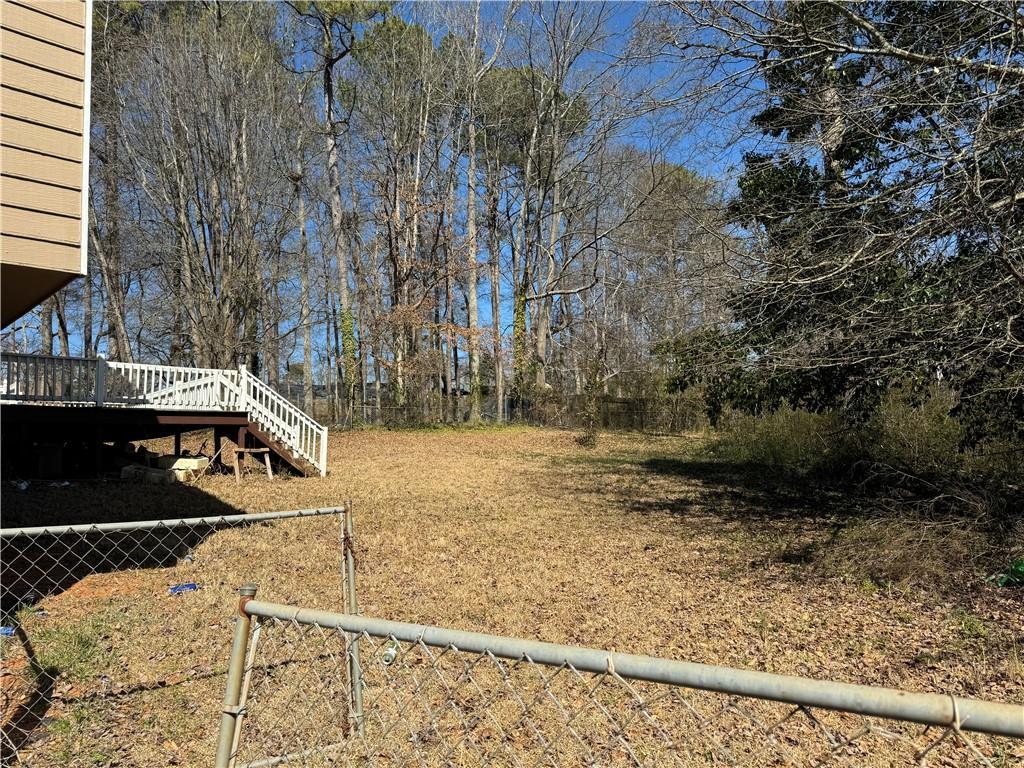 view of yard with fence, a wooden deck, and stairs