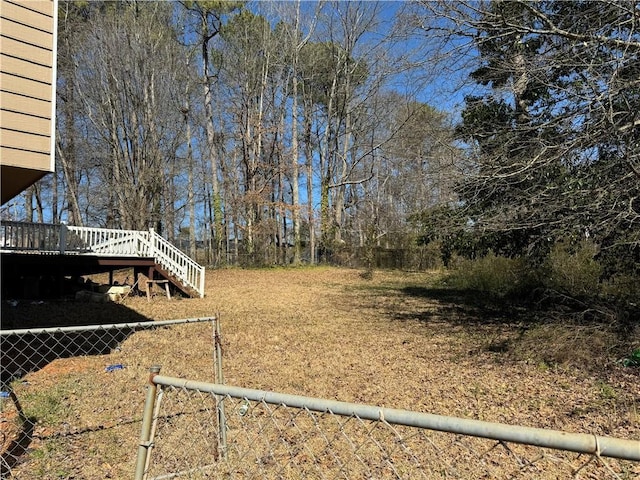 view of yard with fence, a wooden deck, and stairs