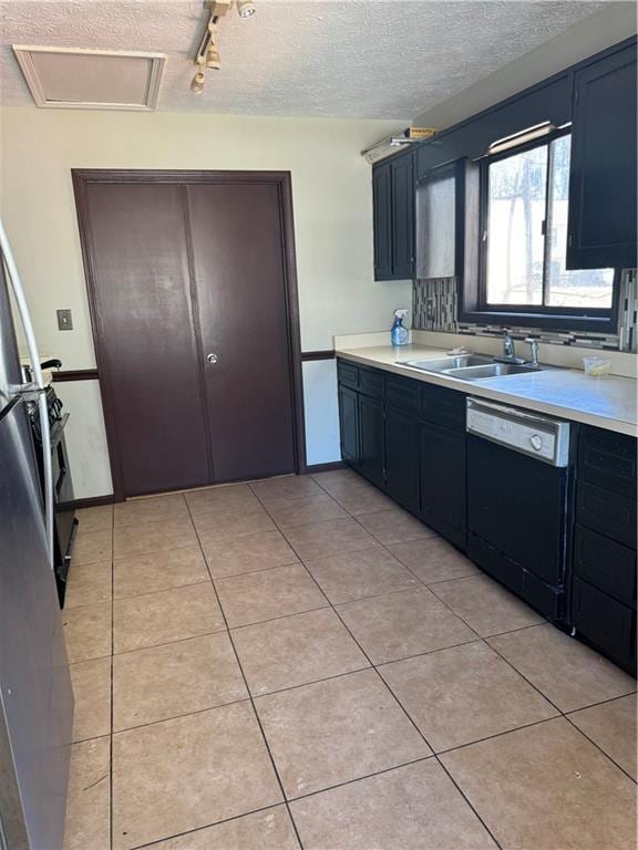 kitchen featuring a textured ceiling, dishwashing machine, light tile patterned flooring, a sink, and light countertops