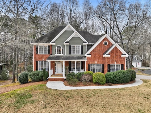 view of front of home featuring brick siding, a porch, and a front lawn