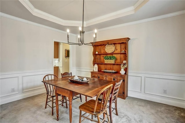 dining area featuring an inviting chandelier, a tray ceiling, a decorative wall, and light carpet