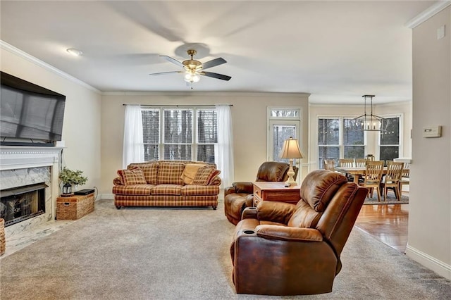 carpeted living room with a fireplace, baseboards, crown molding, and ceiling fan