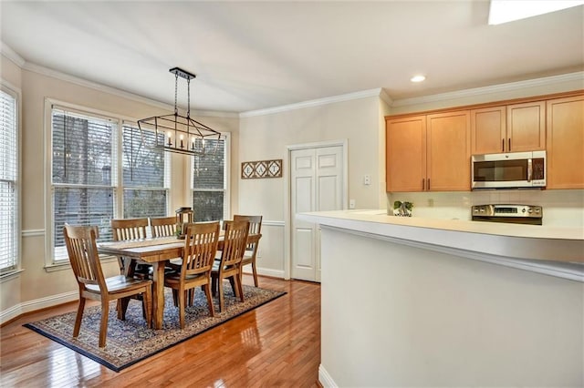 dining room with a wealth of natural light, light wood-style floors, and ornamental molding