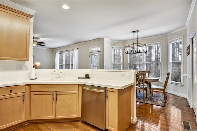 kitchen with a sink, stainless steel dishwasher, a peninsula, and crown molding