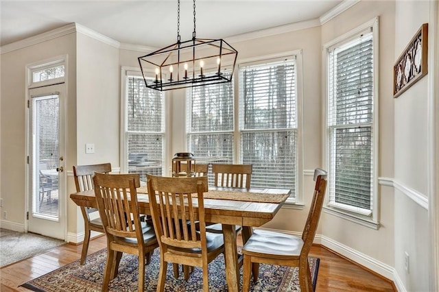 dining area featuring a chandelier, baseboards, wood finished floors, and crown molding