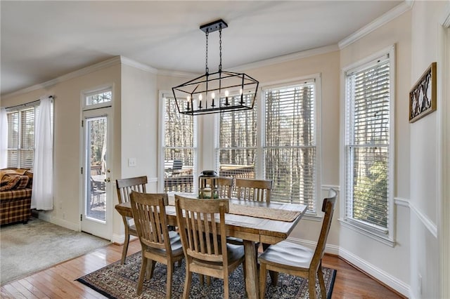 dining space featuring a chandelier, wood finished floors, baseboards, and ornamental molding