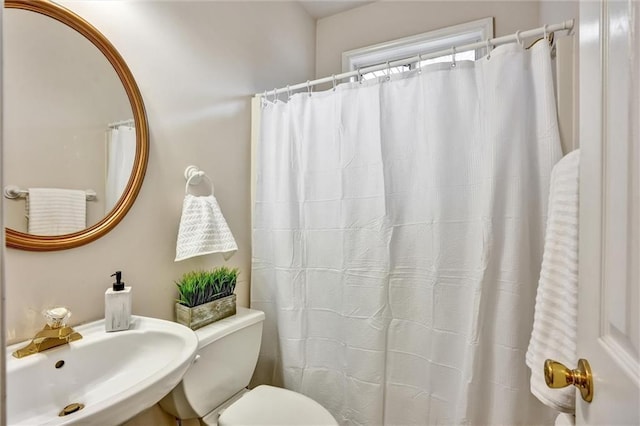 bathroom featuring toilet, a shower with curtain, and a sink