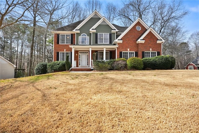 view of front facade featuring brick siding, a porch, and a front yard