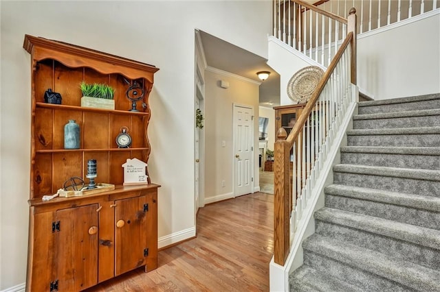 stairs featuring crown molding, baseboards, and wood finished floors