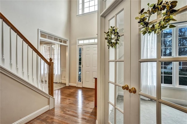 entrance foyer with french doors, baseboards, wood finished floors, and a towering ceiling