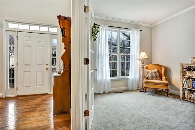 foyer entrance with carpet, crown molding, wood finished floors, and baseboards