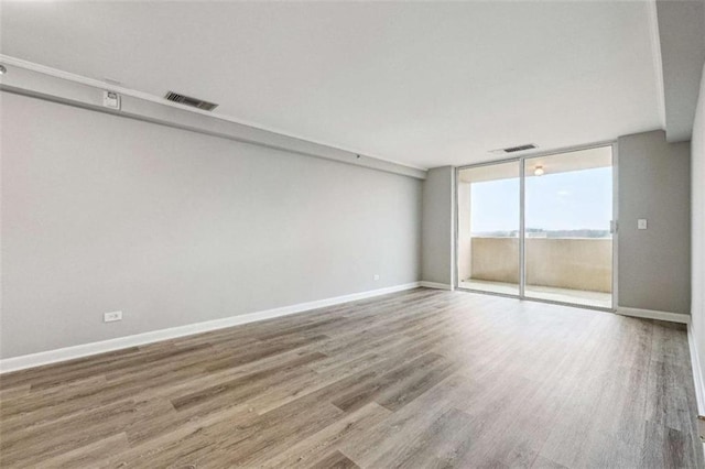 spare room with expansive windows and wood-type flooring