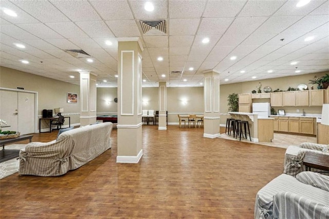 living room featuring light wood-type flooring, a paneled ceiling, and ornate columns