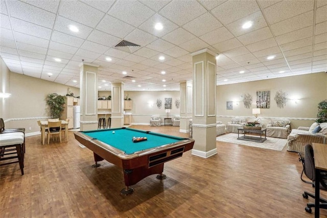 game room featuring billiards, a paneled ceiling, hardwood / wood-style floors, and ornate columns