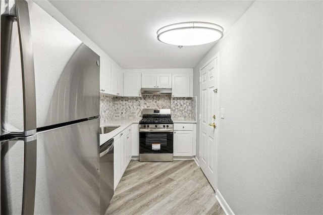 kitchen with stainless steel appliances, white cabinets, backsplash, and light hardwood / wood-style floors