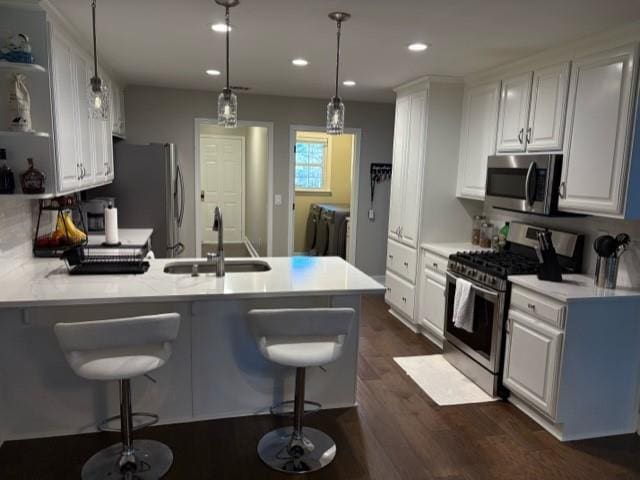 kitchen featuring light countertops, appliances with stainless steel finishes, white cabinets, a sink, and a peninsula