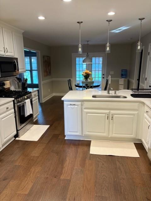 kitchen with stainless steel appliances, dark wood-style flooring, white cabinetry, and a sink