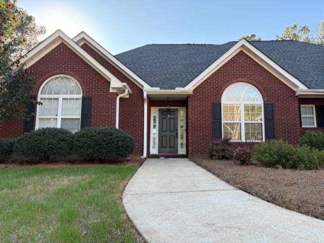 single story home featuring a shingled roof and brick siding