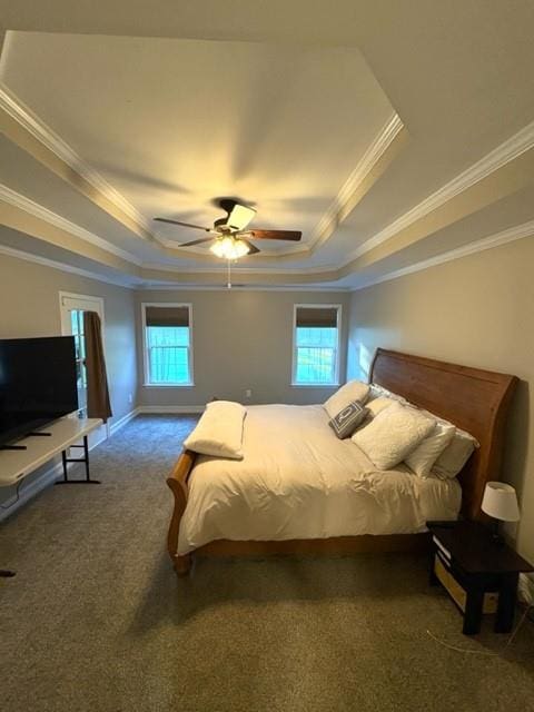 carpeted bedroom featuring multiple windows, a tray ceiling, a ceiling fan, and ornamental molding