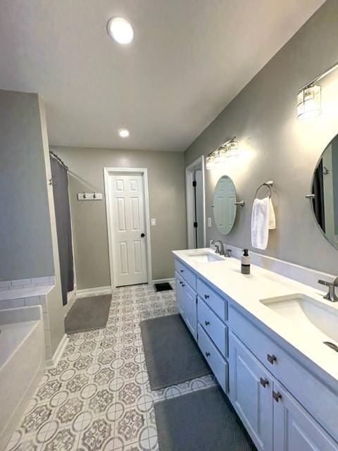 bathroom with tile patterned flooring, a garden tub, a sink, and baseboards