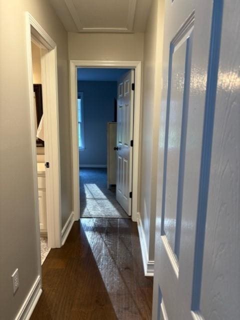 corridor with attic access and baseboards