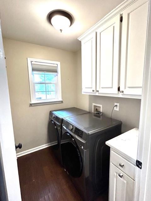 laundry area featuring dark wood-type flooring, washing machine and clothes dryer, cabinet space, and baseboards