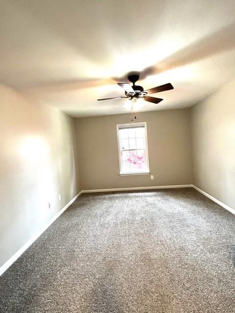 empty room featuring carpet, baseboards, and ceiling fan