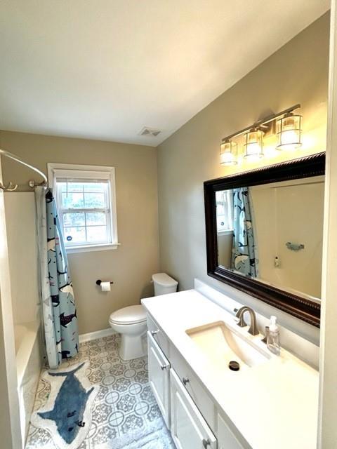 bathroom with baseboards, toilet, tile patterned floors, shower / bathtub combination with curtain, and vanity