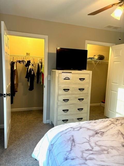 bedroom featuring ceiling fan, dark colored carpet, a closet, and a walk in closet