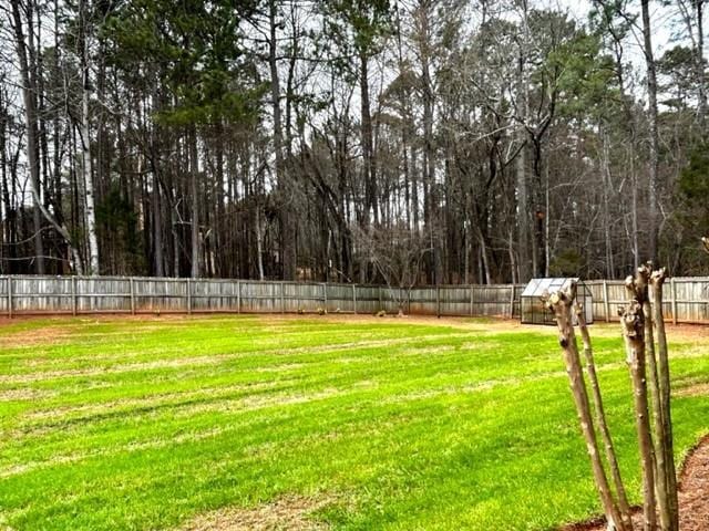 view of yard featuring a fenced backyard, a greenhouse, and an outbuilding