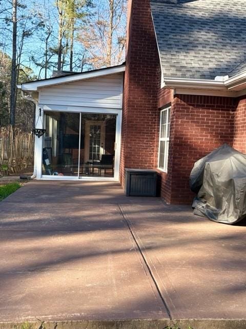 exterior space with a shingled roof, a sunroom, brick siding, and a chimney