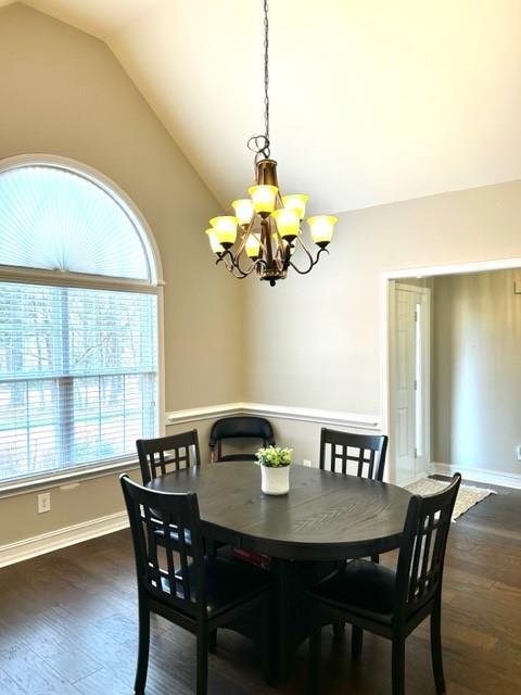 dining space featuring dark wood-style floors, vaulted ceiling, baseboards, and an inviting chandelier