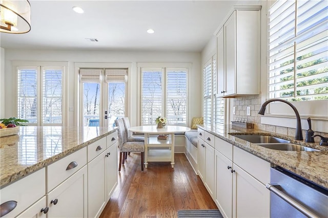 kitchen featuring dark wood finished floors, dishwasher, light stone countertops, white cabinetry, and a sink