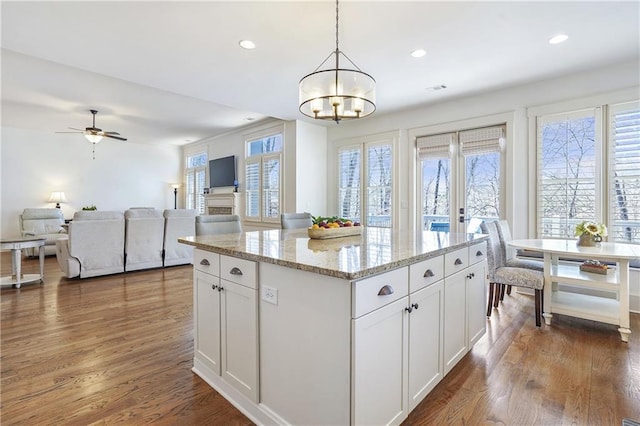 kitchen with open floor plan, hanging light fixtures, white cabinetry, and a center island