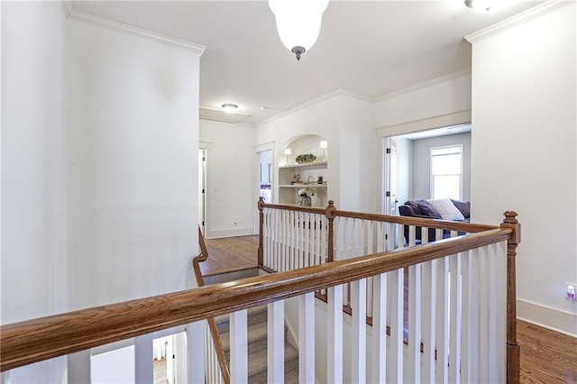 hallway featuring baseboards, crown molding, an upstairs landing, and wood finished floors