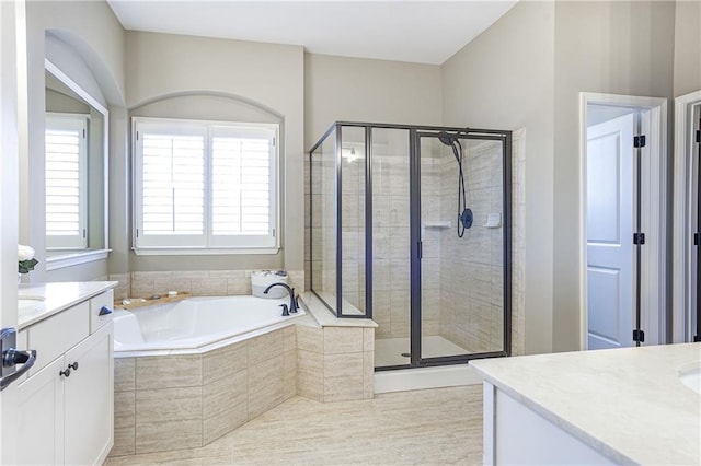 bathroom with a stall shower, a garden tub, and vanity