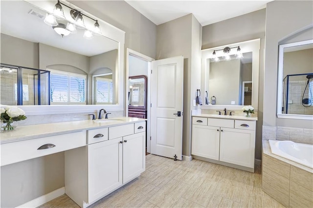 full bath featuring a stall shower, visible vents, two vanities, and a sink