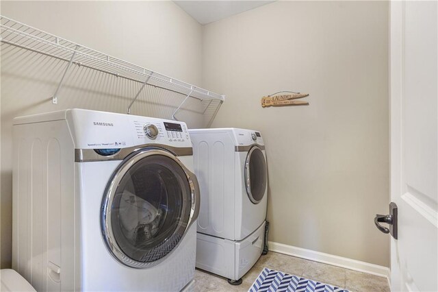 clothes washing area featuring laundry area, light tile patterned floors, baseboards, and washer and dryer