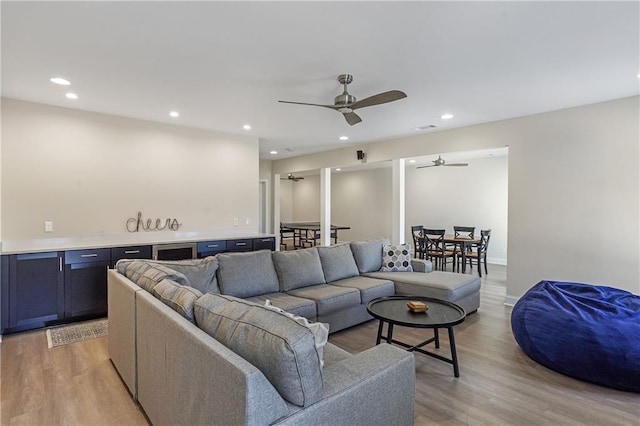 living room featuring baseboards, recessed lighting, a ceiling fan, and light wood-style floors