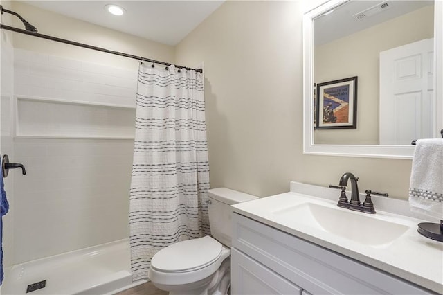 bathroom with visible vents, a tile shower, vanity, and toilet