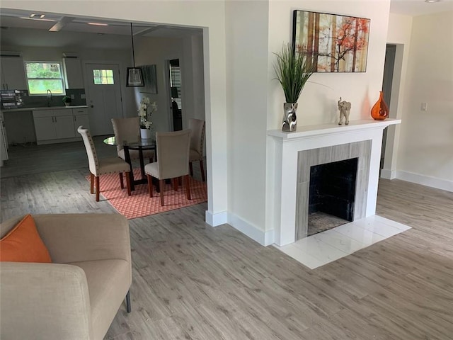 living room with light wood-type flooring, a tile fireplace, and sink