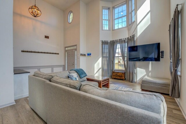 living room featuring a towering ceiling, light hardwood / wood-style flooring, and a notable chandelier