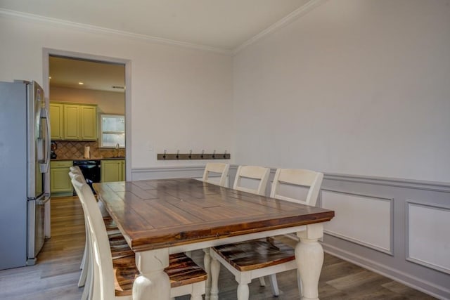 dining space featuring ornamental molding, sink, and light hardwood / wood-style flooring