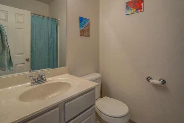 bathroom featuring vanity, curtained shower, and toilet