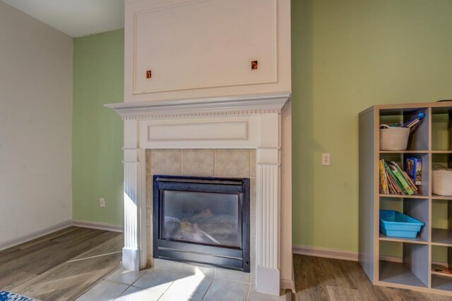 interior details featuring wood-type flooring and a tiled fireplace