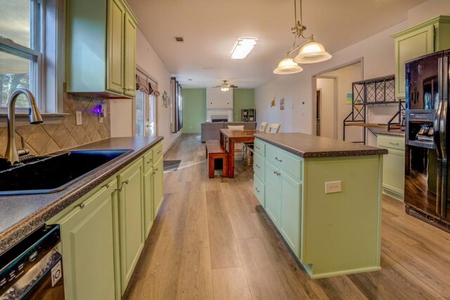 kitchen featuring black appliances, sink, green cabinetry, ceiling fan, and a kitchen island