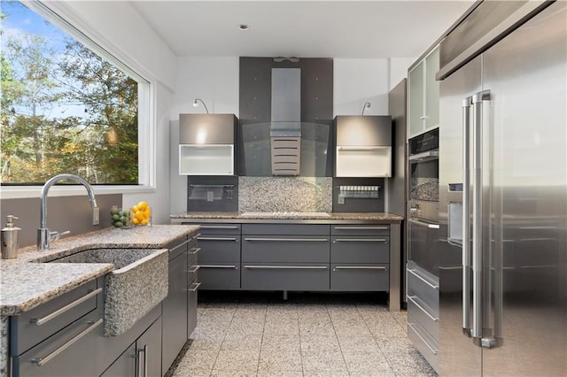 kitchen with high end fridge, backsplash, gray cabinets, and plenty of natural light