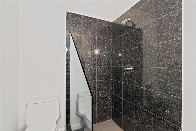 bathroom with a tile shower and toilet