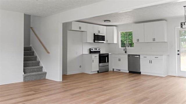 3735 Benchmark Dr, Atlanta, GA 30349 - kitchen with appliances with stainless steel finishes, tasteful backsplash, white cabinetry, light wood-style floors, and a textured ceiling